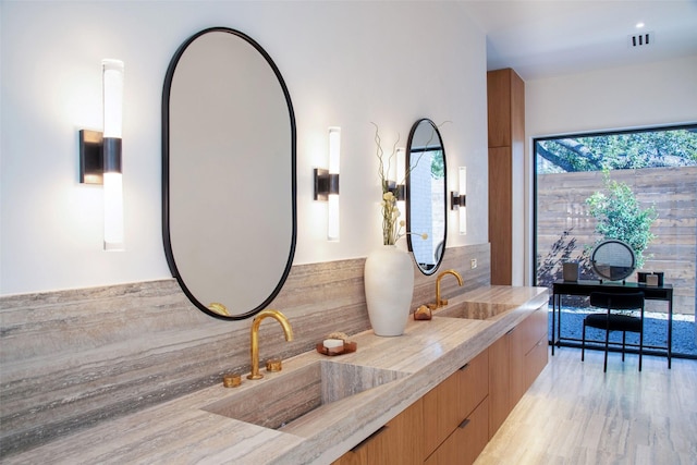 full bathroom with a sink, visible vents, wood finished floors, and double vanity