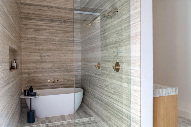 full bathroom with tiled shower and a freestanding bath