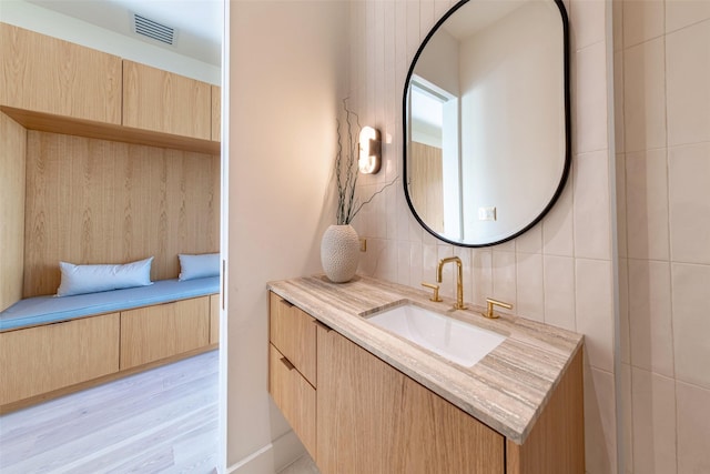 bathroom featuring visible vents, vanity, tile walls, and wood finished floors