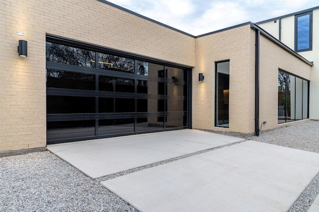 doorway to property with brick siding, concrete driveway, and an attached garage