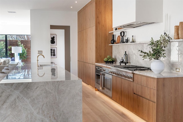 kitchen featuring a sink, backsplash, custom range hood, stainless steel appliances, and modern cabinets