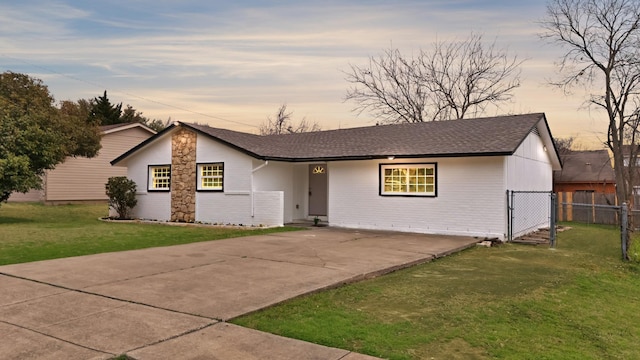 view of front facade featuring concrete driveway, a front lawn, and fence