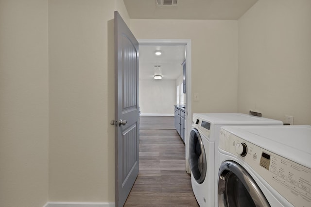 washroom with visible vents, dark wood-style floors, separate washer and dryer, baseboards, and laundry area