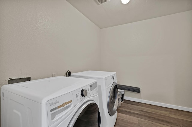 clothes washing area with baseboards, wood finished floors, laundry area, and washer and clothes dryer