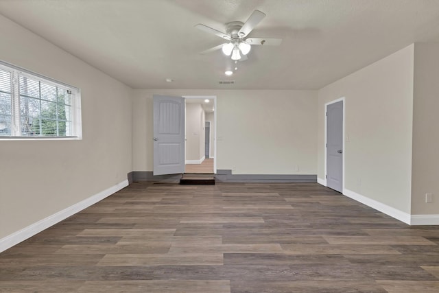 empty room with visible vents, ceiling fan, baseboards, and wood finished floors