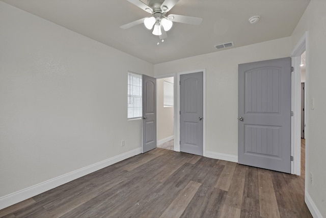 unfurnished bedroom featuring ceiling fan, wood finished floors, visible vents, and baseboards