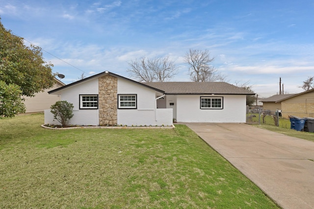 view of front facade with driveway, brick siding, a front yard, and fence