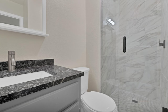 full bath with toilet, a stall shower, vanity, and a textured wall