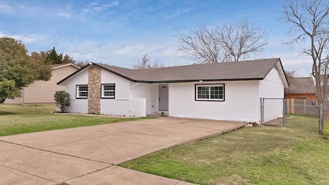 view of front facade featuring fence, concrete driveway, a front yard, a shingled roof, and brick siding