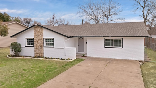 single story home with fence, roof with shingles, concrete driveway, a front yard, and brick siding