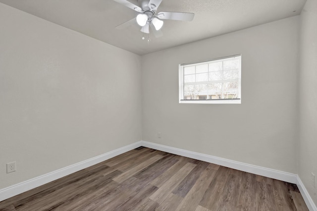 empty room featuring ceiling fan, baseboards, and wood finished floors