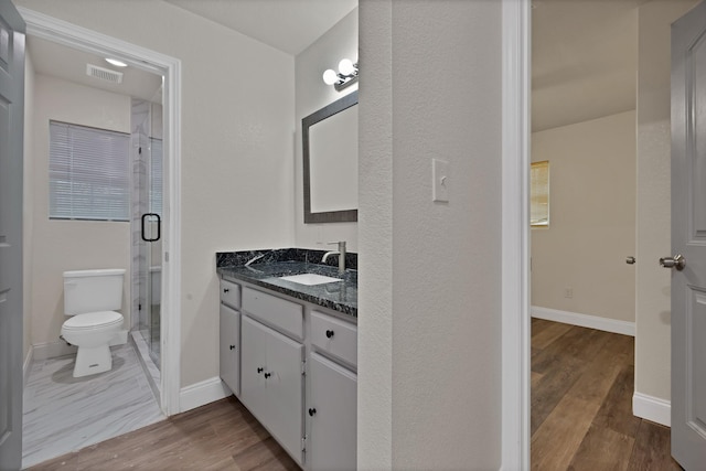 bathroom with a shower stall, baseboards, toilet, wood finished floors, and vanity