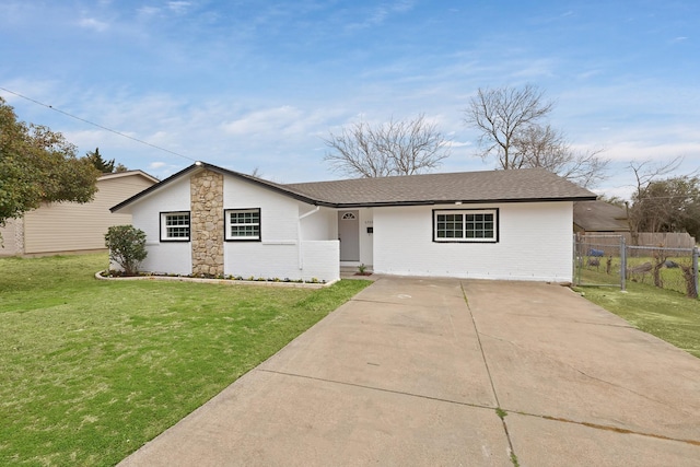 view of front of home with brick siding, concrete driveway, a front lawn, and fence