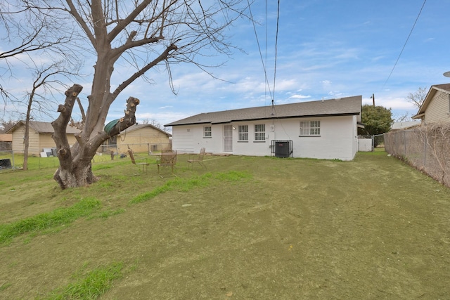 rear view of house with a lawn, central AC, and fence