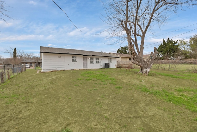 rear view of house with a lawn, central AC unit, and fence