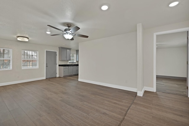 unfurnished living room featuring recessed lighting, a ceiling fan, baseboards, and wood finished floors