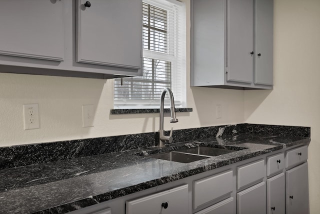 kitchen with dark stone countertops, gray cabinets, and a sink