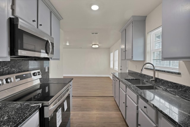 kitchen featuring a wealth of natural light, gray cabinets, appliances with stainless steel finishes, light wood-style flooring, and a sink