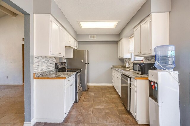 kitchen featuring visible vents, backsplash, baseboards, stainless steel appliances, and white cabinetry