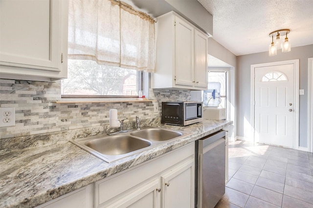 kitchen with a sink, decorative backsplash, stainless steel dishwasher, and white cabinets