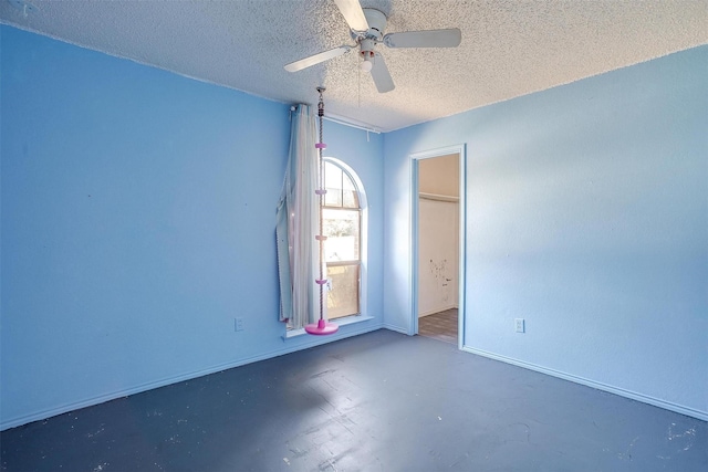 empty room with ceiling fan, a textured ceiling, and finished concrete flooring