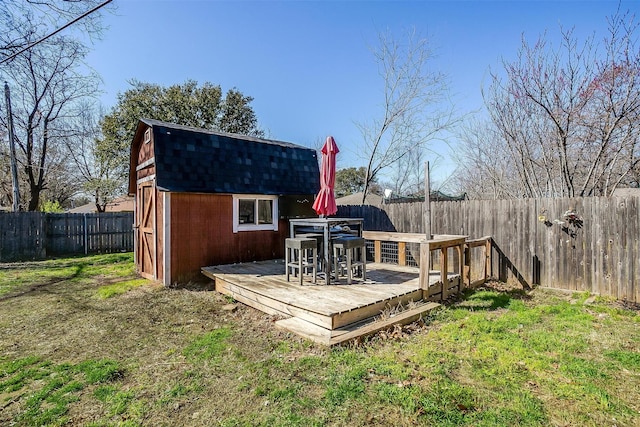 deck with an outdoor structure, a fenced backyard, a lawn, and a shed