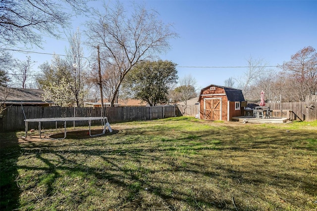 view of yard featuring an outbuilding, a trampoline, a fenced backyard, and a shed