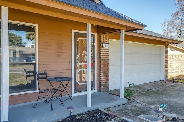 property entrance featuring a garage, brick siding, concrete driveway, and a shingled roof