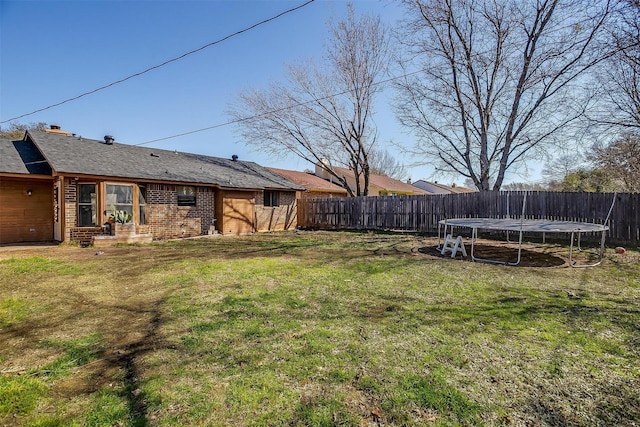 view of yard featuring a fenced backyard and a trampoline