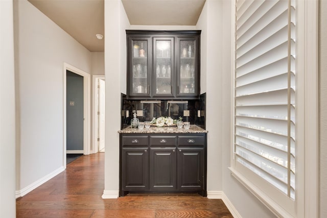 bar with baseboards, a dry bar, and dark wood-style flooring