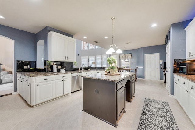 kitchen featuring dishwasher, a peninsula, arched walkways, white cabinets, and a sink