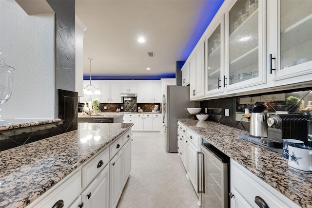 kitchen with white cabinetry, beverage cooler, tasteful backsplash, and light stone countertops