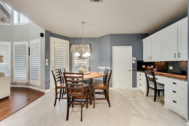 dining area featuring visible vents, baseboards, an inviting chandelier, light tile patterned flooring, and built in study area