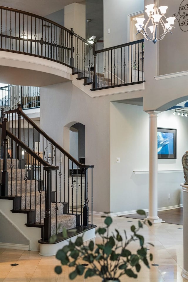 stairs with baseboards, a towering ceiling, tile patterned flooring, and ornate columns