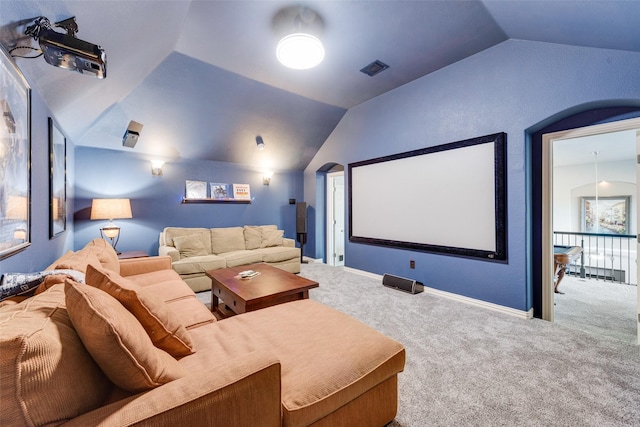 carpeted cinema room with visible vents, lofted ceiling, arched walkways, and baseboards