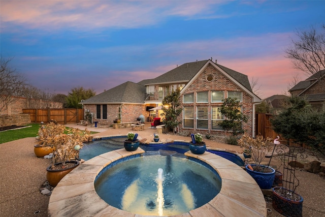 pool at dusk with a patio, a fenced backyard, and a fenced in pool