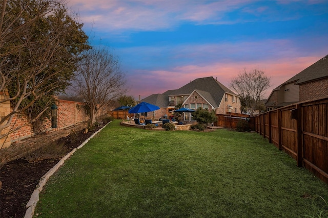 yard at dusk with a patio area and a fenced backyard