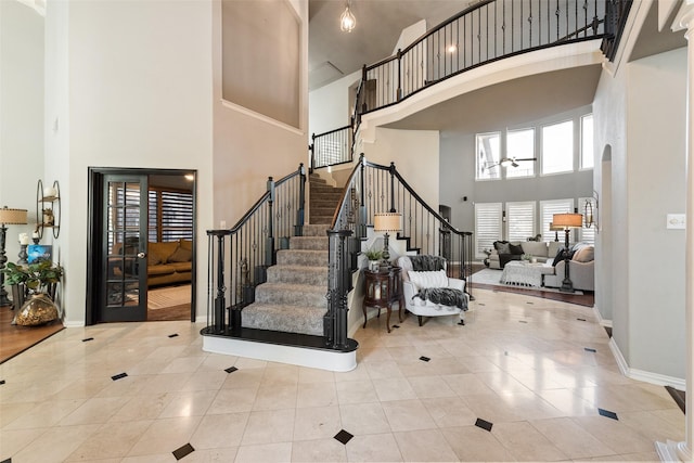 entryway featuring arched walkways, stairway, baseboards, and a towering ceiling