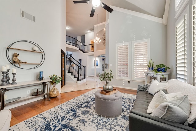 living area with visible vents, high vaulted ceiling, wood finished floors, and stairway