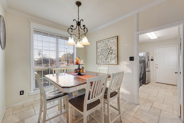 dining room featuring baseboards, separate washer and dryer, stone tile floors, and ornamental molding