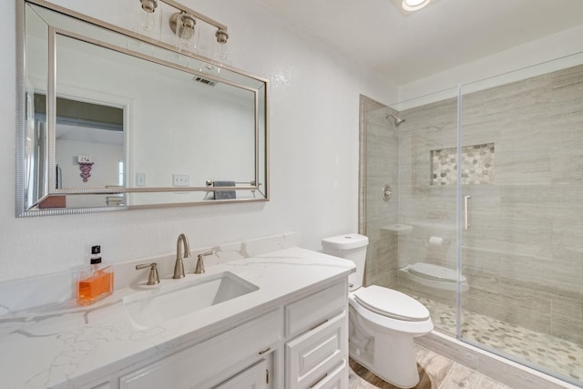 full bathroom with visible vents, a shower stall, toilet, wood finished floors, and vanity