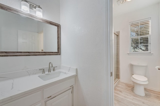 full bathroom featuring a stall shower, toilet, wood finished floors, and vanity