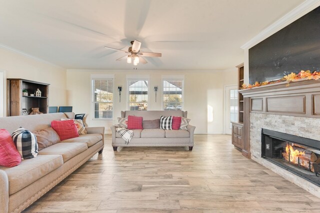 living area featuring a fireplace, a ceiling fan, light wood-style floors, and ornamental molding