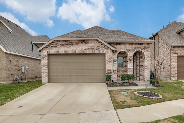 french country inspired facade with brick siding, an attached garage, driveway, and roof with shingles