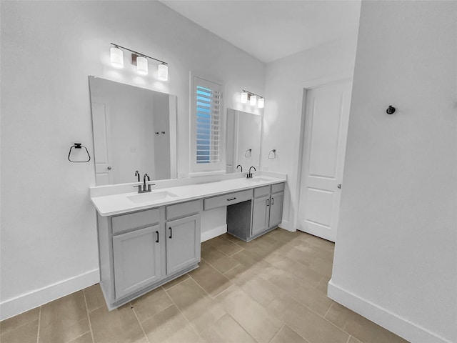 bathroom with a sink, baseboards, and double vanity