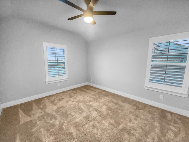 empty room featuring carpet flooring, a ceiling fan, baseboards, and vaulted ceiling