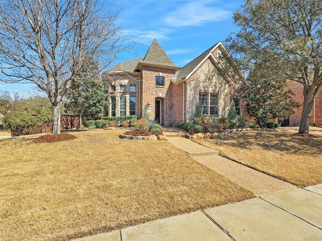 view of front of home featuring a front lawn, brick siding, and roof with shingles