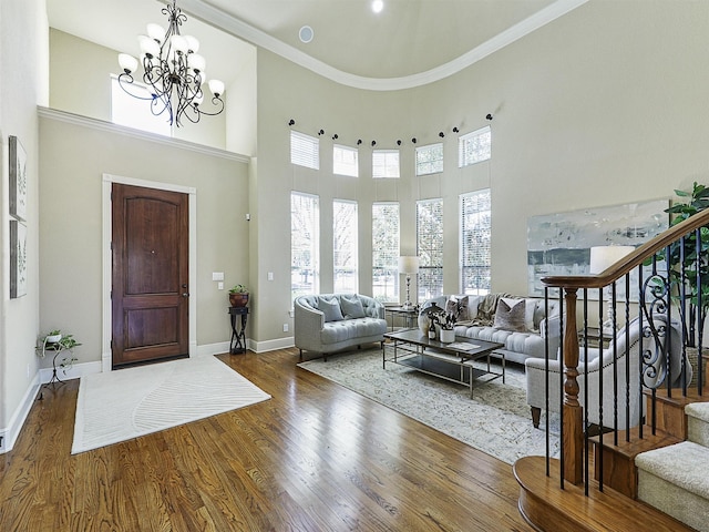 foyer entrance with baseboards, a chandelier, stairway, ornamental molding, and wood finished floors