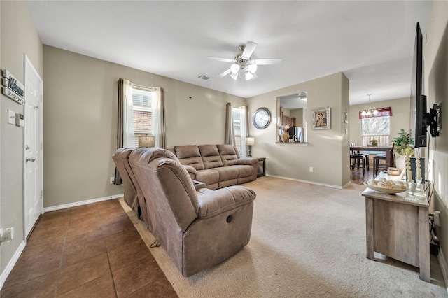 carpeted living room featuring tile patterned floors, visible vents, baseboards, and ceiling fan with notable chandelier