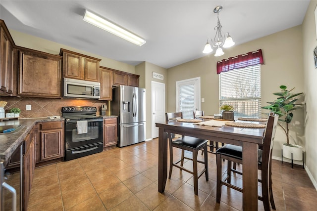 4011 Ridgetop Dr, Heartland, TX 75126 - kitchen with light tile patterned floors, decorative backsplash, appliances with stainless steel finishes, decorative light fixtures, and a notable chandelier